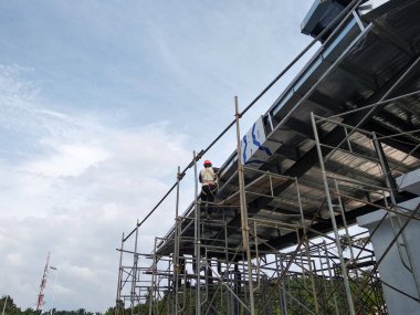 MALACCA, MALAYSIA - 14 Mart 2020: İnşaat işçileri inşaat alanında yükseklerde çalışıyor. Kaza yapmalarını önlemek için onlara emniyet kemeri ve diğer güvenlik ekipmanları sağlanıyor..