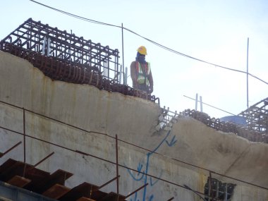 MALACCA, MALAYSIA - 14 Mart 2020: İnşaat işçileri inşaat alanında yükseklerde çalışıyor. Kaza yapmalarını önlemek için onlara emniyet kemeri ve diğer güvenlik ekipmanları sağlanıyor..