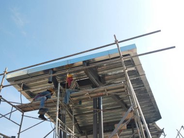 MALACCA, MALAYSIA - 14 Mart 2020: İnşaat işçileri inşaat alanında yükseklerde çalışıyor. Kaza yapmalarını önlemek için onlara emniyet kemeri ve diğer güvenlik ekipmanları sağlanıyor..