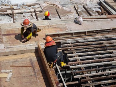 KUALA LUMPUR, MALAYSIA - 16 Temmuz 2017: Marangozlar inşaat alanında kereste ve kontrplak formları üretirler. Güçlendirilmiş beton yapının kalıbı olarak ahşap biçimlendirme.