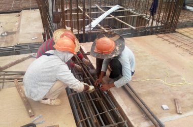 KUALA LUMPUR, MALAYSIA - 20 Haziran 2017: İnşaat işçileri inşaat alanında çelik takviye çubuğu üretiyorlar. Destek çubuğu ince bir kabloyla birbirine bağlanmış..