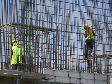 KUALA LUMPUR, MALAYSIA - 20 Haziran 2017: İnşaat işçileri inşaat alanında çelik takviye çubuğu üretiyorlar. Destek çubuğu ince bir kabloyla birbirine bağlanmış..
