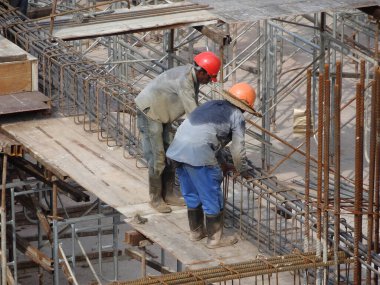KUALA LUMPUR, MALAYSIA - 20 Haziran 2017: İnşaat işçileri inşaat alanında çelik takviye çubuğu üretiyorlar. Destek çubuğu ince bir kabloyla birbirine bağlanmış..