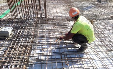 KUALA LUMPUR, MALAYSIA - 20 Haziran 2017: İnşaat işçileri inşaat alanında çelik takviye çubuğu üretiyorlar. Destek çubuğu ince bir kabloyla birbirine bağlanmış..