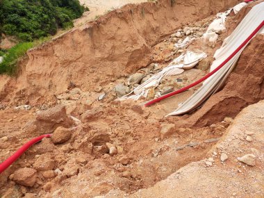 Şiddetli yağmur nedeniyle toprak kayması. Heyelan yeraltı su borularını yok ediyor ve bazı insanlar binalar inşa ediyor.. 