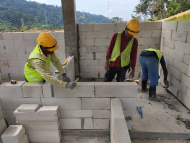 SEREMBAN, MALAYSIA -MARCH 17, 2020: Blockwork by construction workers at the construction site. Workers laying the AAC brick and stacked it together using mortar to form the wall. 