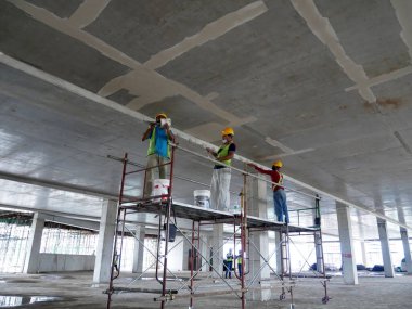 KUALA LUMPUR, MALAYSIA -APRIL 16, 2020: Construction site workers are doing ceiling soffit skim coat work at the construction site. Two layers base and final coat apply to get the smooth surface. 
