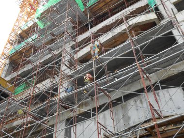 MALACCA, MALAYSIA -MAC 29, 2017: İnşaat işçileri inşaat alanında yüksekken metal yapı iskelesi kullandılar. Bunu yapmak için gerekli güvenlik ekipmanlarını giymeleri gerekiyor.. 