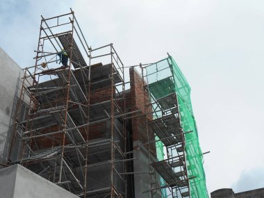 MALACCA, MALAYSIA -MAC 29, 2017: İnşaat işçileri inşaat alanında yüksekken metal yapı iskelesi kullandılar. Bunu yapmak için gerekli güvenlik ekipmanlarını giymeleri gerekiyor.. 
