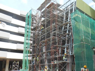 MALACCA, MALAYSIA -MAC 29, 2017: İnşaat işçileri inşaat alanında yüksekken metal yapı iskelesi kullandılar. Bunu yapmak için gerekli güvenlik ekipmanlarını giymeleri gerekiyor.. 