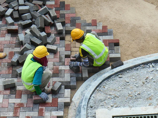 SEREMBAN, MALAYSIA - HAZİRAN 06, 2017: İnşaat işçileri inşaat alanındaki yol için önceden yapılmış beton kaldırım taşlarını kuruyor ve düzenliyor. 