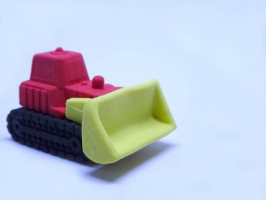 Beyaz arka planda izole edilmiş renkli sentetik kauçuktan yapılmış buldozer maketi.. 