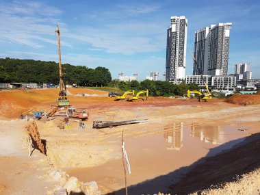 CYBERJAYA, MALAYSIA - 10 HAZİRAN 2020: Yeni gelişim alanı için toprak çalışmaları. Yokuş, ağır makinelerle budanmış. Arazi mühendisi gerekli platform seviyesini saptamaya yardım ediyor. Dünyayı kesmek ya da doldurmak için kullanılan makineler. 