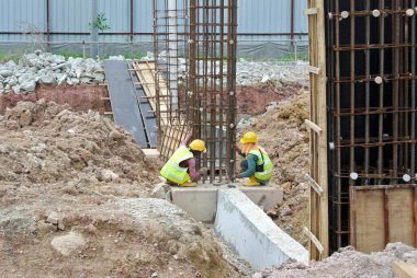 JOHOR, MALAYSIA -18 Ocak 2017: Johor, Malezya 'daki inşaat alanında çelik takviye barı üreten inşaat işçileri. Destek çubuğu ince kabloyla birbirine bağlıydı.. 