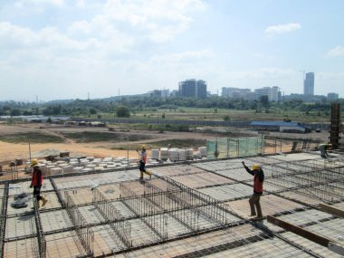 JOHOR, MALAYSIA -18 Ocak 2017: Johor, Malezya 'daki inşaat alanında çelik takviye barı üreten inşaat işçileri. Destek çubuğu ince kabloyla birbirine bağlıydı.. 