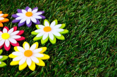 Renkli kumaşlardan yapılmış çiçeklerin görüntüleri. Yapay çimlerin üzerinde izole edilmiş.. 