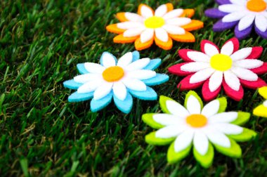 Renkli kumaşlardan yapılmış çiçeklerin görüntüleri. Yapay çimlerin üzerinde izole edilmiş.. 