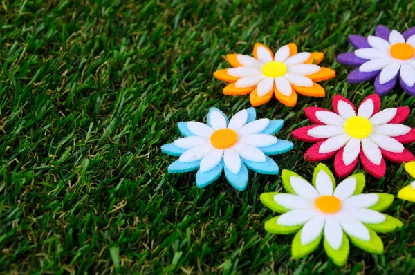 Renkli kumaşlardan yapılmış çiçeklerin görüntüleri. Yapay çimlerin üzerinde izole edilmiş.. 