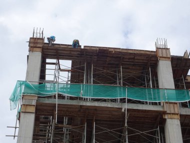 MALACCA, MALAYSIA - 14 Mart 2020: İnşaat işçileri inşaat alanında yükseklerde çalışıyor. Kaza yapmalarını önlemek için onlara emniyet kemeri ve diğer güvenlik ekipmanları sağlanıyor..