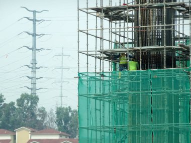 MALACCA, MALAYSIA - 14 Mart 2020: İnşaat işçileri inşaat alanında yükseklerde çalışıyor. Kaza yapmalarını önlemek için onlara emniyet kemeri ve diğer güvenlik ekipmanları sağlanıyor..