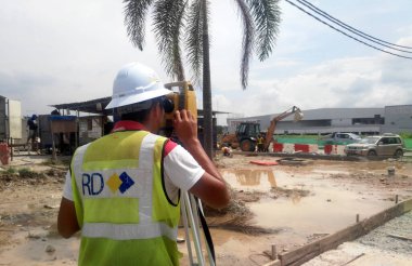 MALACCA, MALAYSIA -APRIL 21, 2016: İnşaat alanındaki araştırma ekipmanlarıyla birlikte araştırmacı. Seviyeyi belirlemek ve kontrol etmek için bu ekipmanı kullanıyor..   