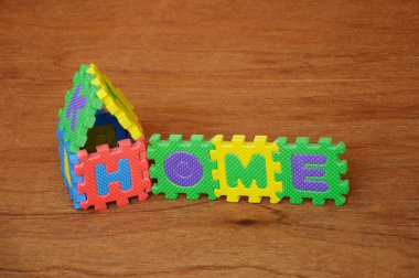 Renkli yumuşak kauçuk paspastan yapılmış ev yapımı bir kelime. Ahşap doku arka planında izole edilmiş.. 