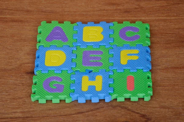 Rubber mat with colourful alphabet design isolated on wood texture board as background.