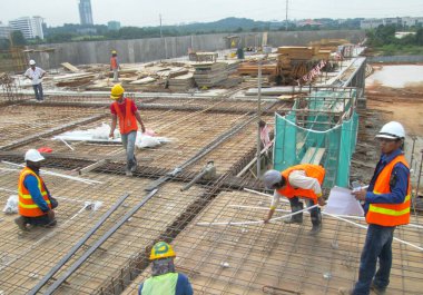SEREMBAN, MALAYSIA - 31 HAZİRAN 2017: İnşaat işçileri gün içinde şantiyede çalışıyorlar. Güvenliklerini sağlamak için düzgün ve uygun güvenlik giysileri giymeleri gerekiyor..  