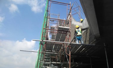 JASIN, MALAYSIA -14 HAZİRAN 2017: Malezya 'nın Jasin kentindeki inşaat sahasında çimento ve kum karışımı kullanarak inşaat duvarlarını ve kirişleri alçılayan inşaat işçileri