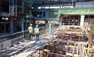 MALACCA, MALAYSIA - 25 Şubat 2017: İnşaat işçileri gün içinde şantiyede çalışıyor. Güvenliklerini sağlamak için düzgün ve uygun güvenlik giysileri giymeleri gerekiyor..  