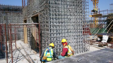 MALACCA, MALAYSIA - 25 Şubat 2017: İnşaat işçileri gün içinde şantiyede çalışıyor. Güvenliklerini sağlamak için düzgün ve uygun güvenlik giysileri giymeleri gerekiyor..  