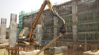 SELANGOR, MALAYSIA 15 Nisan 2016: İnşaat alanındaki çarşaf yığını cofferdam sürücü makinesi. Makine titreşimli hidrolik kolu kullanarak çarşaf yığınını yere itti. İşçi kontrolü. 