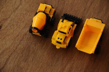Küçük bir inşaat makinesi oyuncağı, kamyon, buldozer ve beton karıştırıcı grubu. Hepsi de ahşap dokuda izole edilmiş plastikten yapılmış..