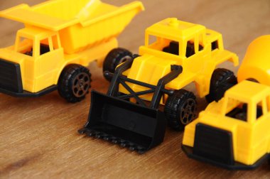 Küçük bir inşaat makinesi oyuncağı, kamyon, buldozer ve beton karıştırıcı grubu. Hepsi de ahşap dokuda izole edilmiş plastikten yapılmış..