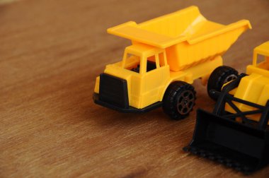 Küçük bir inşaat makinesi oyuncağı, kamyon, buldozer ve beton karıştırıcı grubu. Hepsi de ahşap dokuda izole edilmiş plastikten yapılmış..