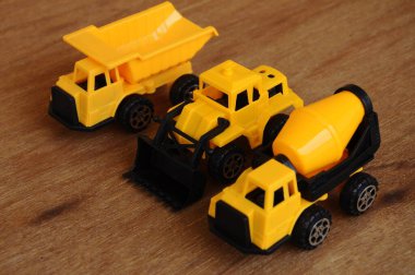 Küçük bir inşaat makinesi oyuncağı, kamyon, buldozer ve beton karıştırıcı grubu. Hepsi de ahşap dokuda izole edilmiş plastikten yapılmış..