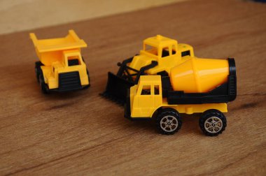 Küçük bir inşaat makinesi oyuncağı, kamyon, buldozer ve beton karıştırıcı grubu. Hepsi de ahşap dokuda izole edilmiş plastikten yapılmış..