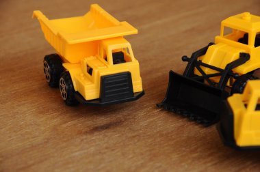 Küçük bir inşaat makinesi oyuncağı, kamyon, buldozer ve beton karıştırıcı grubu. Hepsi de ahşap dokuda izole edilmiş plastikten yapılmış..