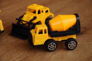 Küçük bir inşaat makinesi oyuncağı, kamyon, buldozer ve beton karıştırıcı grubu. Hepsi de ahşap dokuda izole edilmiş plastikten yapılmış..