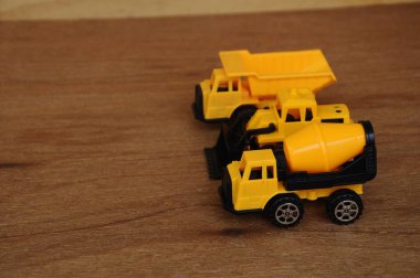 Küçük bir inşaat makinesi oyuncağı, kamyon, buldozer ve beton karıştırıcı grubu. Hepsi de ahşap dokuda izole edilmiş plastikten yapılmış..