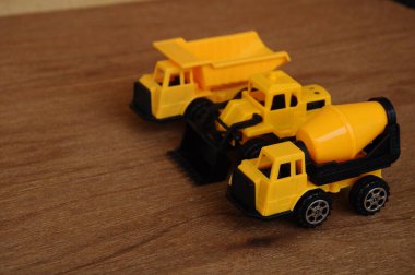 Küçük bir inşaat makinesi oyuncağı, kamyon, buldozer ve beton karıştırıcı grubu. Hepsi de ahşap dokuda izole edilmiş plastikten yapılmış..