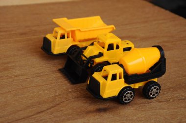 Küçük bir inşaat makinesi oyuncağı, kamyon, buldozer ve beton karıştırıcı grubu. Hepsi de ahşap dokuda izole edilmiş plastikten yapılmış..