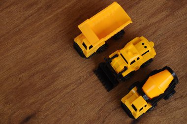 Küçük bir inşaat makinesi oyuncağı, kamyon, buldozer ve beton karıştırıcı grubu. Hepsi de ahşap dokuda izole edilmiş plastikten yapılmış..