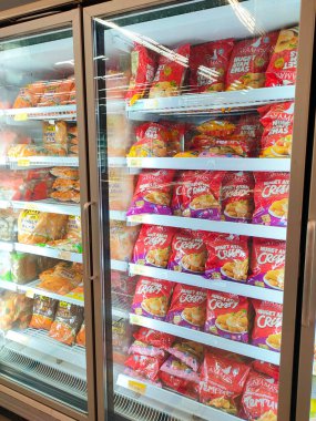 KUALA LUMPUR, MALAYSIA -APRIL 16, 2021: Dev süpermarketteki soğutucu buzdolabının içine yerleştirilmiş çeşitli markalarda ticari paketleme tavuk nuggetı üzerine odaklanmış.