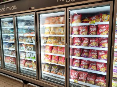 KUALA LUMPUR, MALAYSIA -APRIL 16, 2021: Dev süpermarketteki soğutucu buzdolabının içine yerleştirilmiş çeşitli markalarda ticari paketleme tavuk nuggetı üzerine odaklanmış.