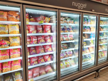 KUALA LUMPUR, MALAYSIA -APRIL 16, 2021: Dev süpermarketteki soğutucu buzdolabının içine yerleştirilmiş çeşitli markalarda ticari paketleme tavuk nuggetı üzerine odaklanmış.