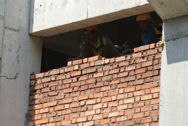 SELANGOR, MALAYSIA -15 HAZİRAN 2017: Tuğlacı inşaat alanında inşaat duvarları oluşturmak için kil tuğlalar döşedi. 