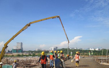 MALACCA, MALAYSIA -HAZİRAN 31, 2017: İnşaat işçileri inşaat sahasındaki beton pompalama makinesinin beton hortumunu kullanarak inşaat alanındaki döşeme kaplamasına döküyorlar.  