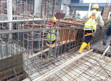 KUALA LUMPUR, MALAYSIA -14 HAZİRAN 2017: İnşaat işçileri inşaat alanında çelik takviye çubuğu üretiyorlar. Destek çubuğu küçük bir kabloyla birbirine bağlanmış..    