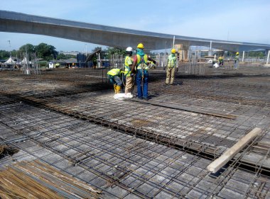 KUALA LUMPUR, MALAYSIA -14 HAZİRAN 2017: İnşaat işçileri inşaat alanında çelik takviye çubuğu üretiyorlar. Destek çubuğu küçük bir kabloyla birbirine bağlanmış..    